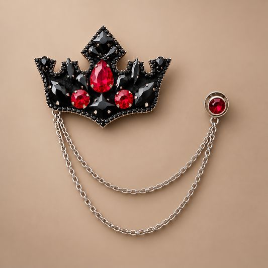 The Royalty Crown Brooch flat lay — full detail of black crystal crown, ruby centerpiece, and double silver chain