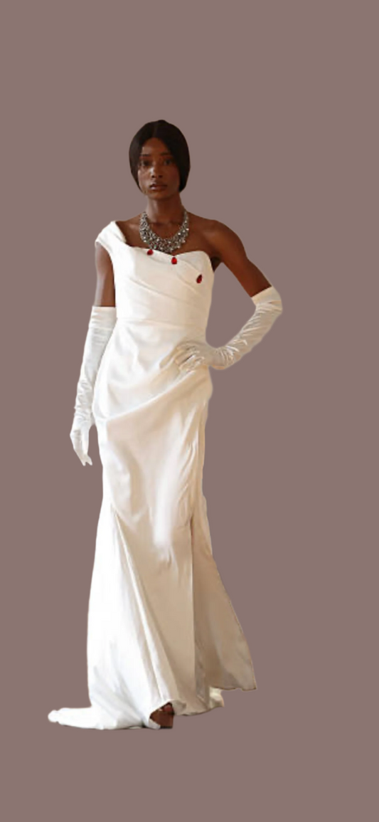Crafted in lustrous white satin, this striking floor-length gown features an asymmetrical neckline adorned with elegant red button detailing, creating a bold yet timeless silhouette.